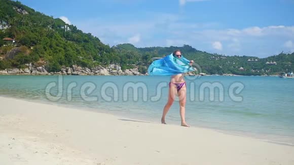 一个带着帕雷奥的年轻女孩在海滩的岸边热带小岛夏日的暖风视频的预览图