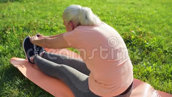 可爱的老年妇女在公园里做伸展运动视频的预览图