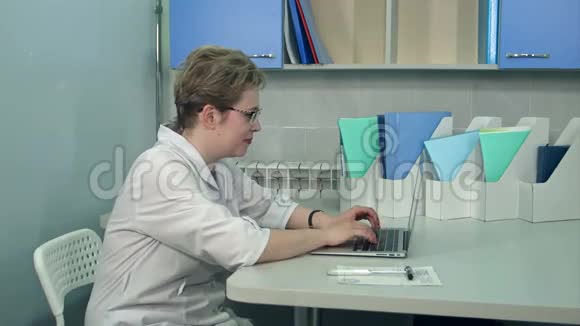 戴眼镜的女医生在诊所用手提电脑视频的预览图