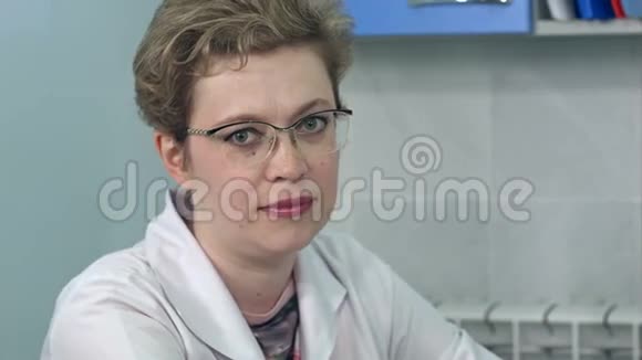 戴眼镜的女医生坐在办公桌前直视镜头视频的预览图