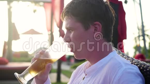 那个坐在户外餐馆喝啤酒的家伙日落时间视频的预览图