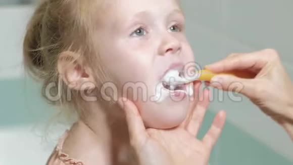 妈妈轻轻地刷牙她心爱的女儿的牙齿一个小女孩和她的母亲轻轻地清洁牙齿后吃视频的预览图