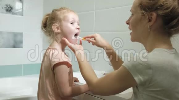 妈妈轻轻地刷牙她心爱的女儿的牙齿一个小女孩和她的母亲轻轻地清洁牙齿后吃视频的预览图
