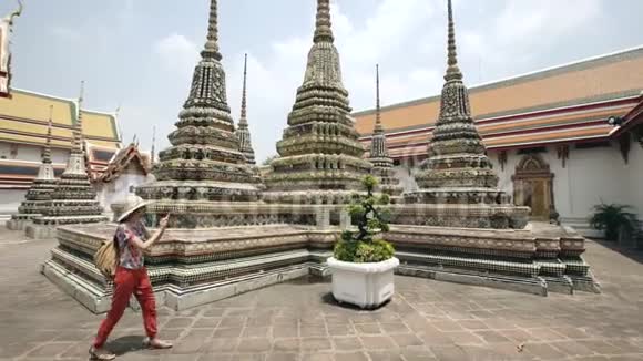 泰国曼谷寺庙观光的年轻女游客用智能手机拍照视频的预览图