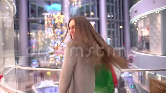 美丽的女人为圣诞节买礼物购物中心的买家手里拿着大的多色包裹圣诞节视频的预览图