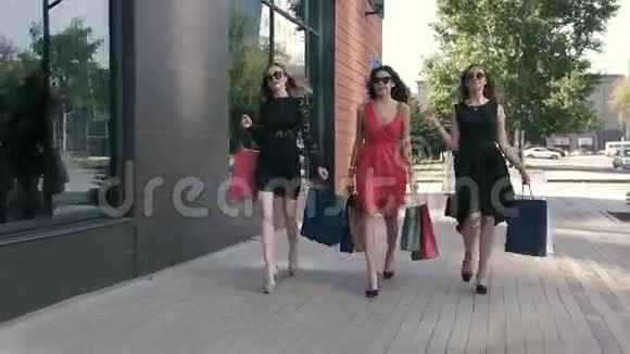 三位漂亮的年轻女士正拿着她们买的东西散步视频的预览图