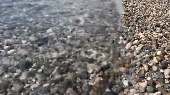 沙滩上像水一样的视频洗过彩色的美丽鹅卵石视频的预览图
