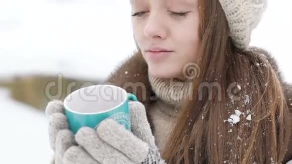 在寒冷的冬天漂亮的女孩拿着一杯热饮料慢慢地视频的预览图