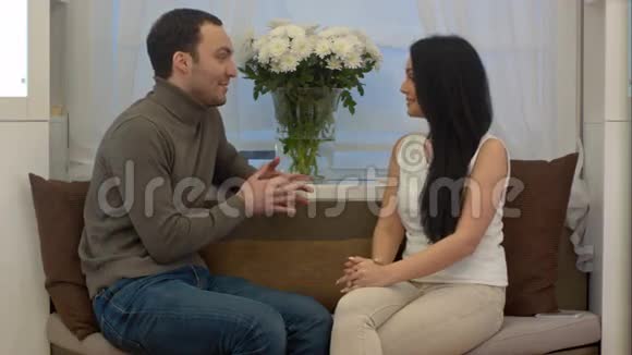 一个英俊的男人在客厅里带着礼物给他的女朋友视频的预览图