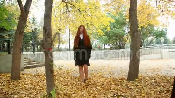 穿着黑色外套的女孩头发粗糙沿着秋天的公园散步视频的预览图