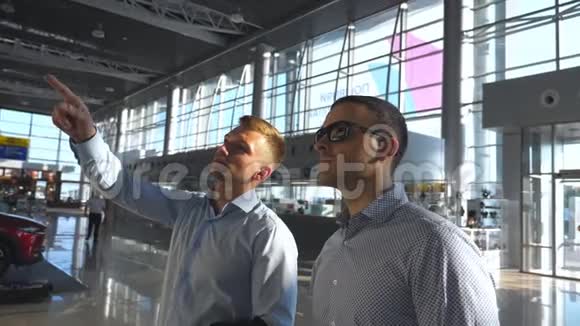 商人在时间表屏幕上用太阳镜指着他的同事两个年轻的商人视频的预览图
