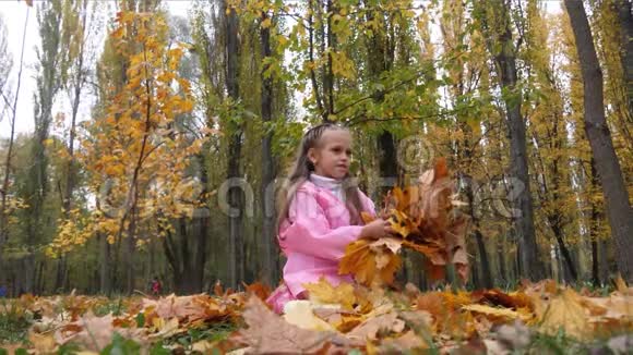 有趣欢快可爱的小女孩跳着黄色秋天落叶慢动作视频的预览图