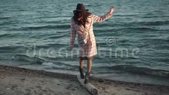 秋装可爱的女孩在日落时沿着海滩散步年轻的女人在水上享受温暖的秋日那个女孩视频的预览图