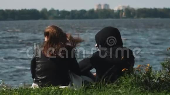 在一个夏天刮风的日子里一对夫妇坐在湖边的草地上聊天视频的预览图