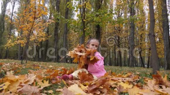 有趣欢快可爱的小女孩跳着黄色秋天落叶慢动作视频的预览图