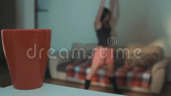 早上一个年轻的运动女孩在客厅里用球做伸展运动视频的预览图