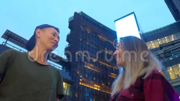 年轻漂亮的亚洲夫妇男人和女孩站在城市的街道上互相交谈视频的预览图