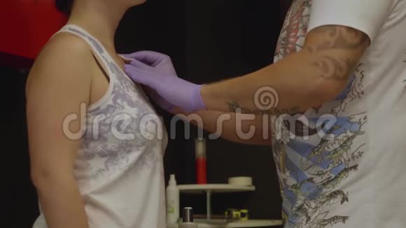 纹身艺术家在手套擦拭棉垫部分客户的皮肤准备纹身视频的预览图