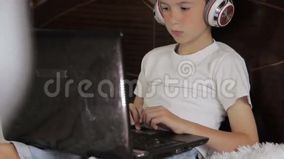 这个男孩躺在床上听音乐或者用他的平板电脑上一节电子学习课它连接着一对视频的预览图