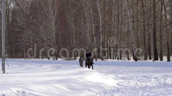 一个女孩驰骋在马背上一匹马正用绳子拖着一个滑雪者一个滑雪者骑在sn的滑雪板上视频的预览图