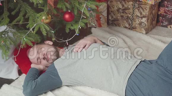 不断下跌的美元一个男人睡在圣诞树附近视频的预览图