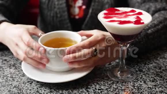 漂亮的女孩温暖了她的手拿着一杯热的红茶或绿茶视频的预览图