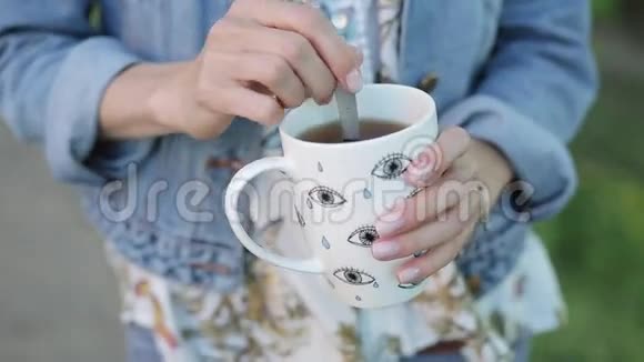 女孩混合她的饮料在一个白色的杯子里合上一杯茶视频的预览图