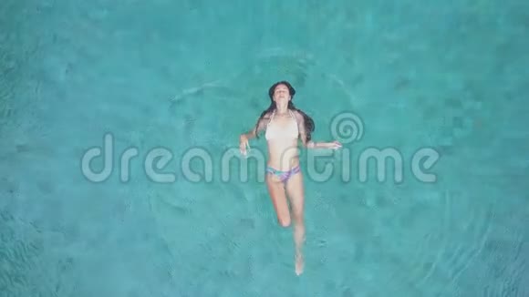 女孩在游泳池里游泳空中景观视频的预览图