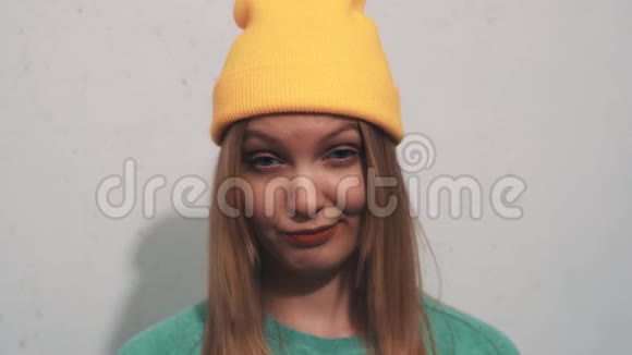 穿着绿色运动衫戴着黄色豆帽的漂亮女孩眉毛上扬带着暗示视频的预览图