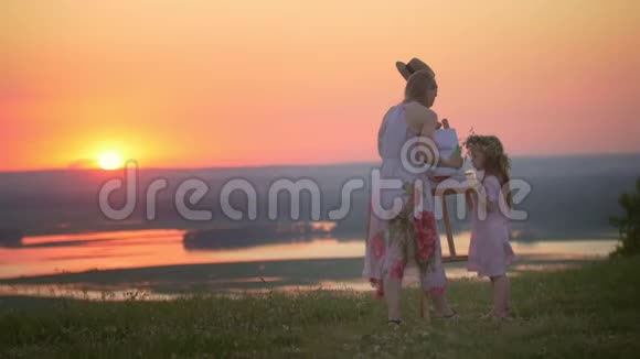 美丽的母女在夕阳山上画大自然视频的预览图