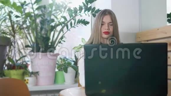 一位年轻严肃的女士在咖啡馆里用笔记本电脑打字视频的预览图
