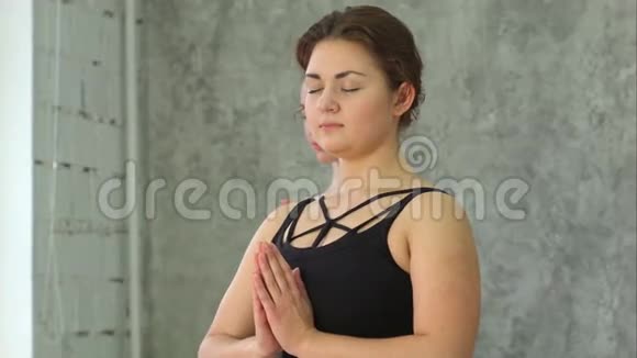 年轻漂亮的运动女孩用闭上眼睛和手掌练习室内瑜伽的肖像视频的预览图