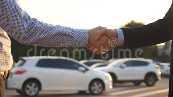 两个商人在户外握手穿衬衫的男人把车钥匙给他的朋友商人的手臂视频的预览图