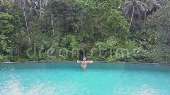 女孩在游泳池里游泳空中景观视频的预览图