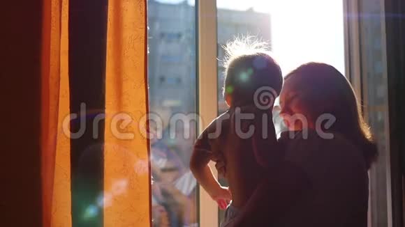 窗前的女孩在阳光下亲吻一个孩子视频的预览图