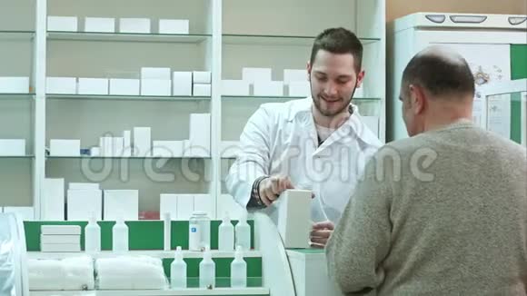 年轻药剂师在药店给老年顾客送药并支付美金视频的预览图