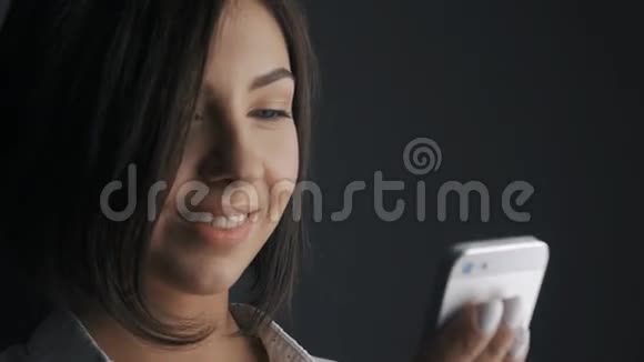 接近迷人的商业女性微笑因为她使用她的触摸屏电话视频的预览图
