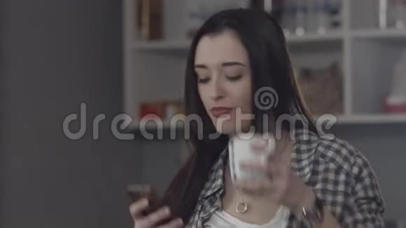 女人喝咖啡看智能手机视频的预览图