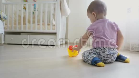 多莉后视镜头可爱的小男孩坐在房间里玩玩具车视频的预览图
