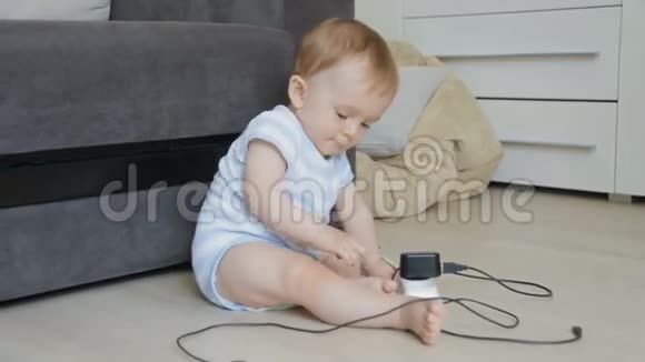 婴儿独自坐在房间里玩插座和充电线的概念婴儿在危险中幼儿玩电线和CA视频的预览图
