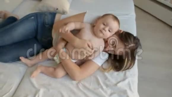 幸福的年轻母亲在床上挠她的小儿子视频的预览图