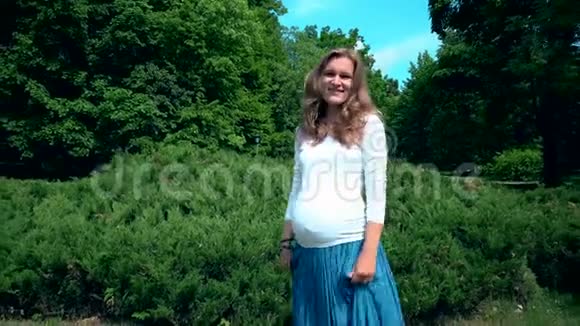 夏日阳光下美丽的孕妇在公园散步视频的预览图