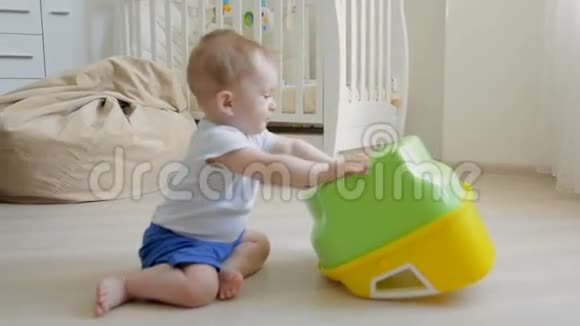 可爱的蹒跚学步的男孩在地板上爬行玩陶器视频的预览图