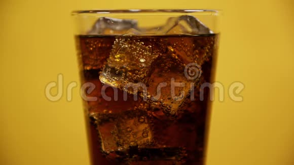 盛满可乐的玻璃杯喝冰块冷汽水黄色背景视频的预览图