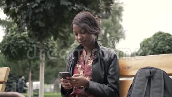 一幅美丽的非洲年轻女子在大学毕业后坐在长凳上微笑的画像视频的预览图