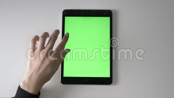 女性手在平板电脑上滚动绿色屏幕色度概念顶拍60fps视频的预览图