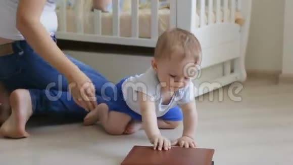 可爱的小男孩爬在地板上试图打开大书视频的预览图