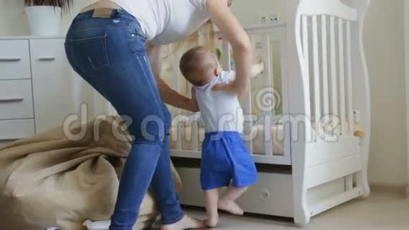 可爱的蹒跚学步的男孩在妈妈把他放进婴儿床后开始哭视频的预览图