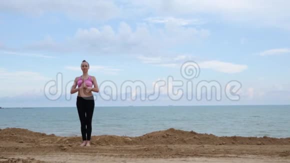 女孩练习瑜伽健身运动在海边的勇士姿势视频的预览图