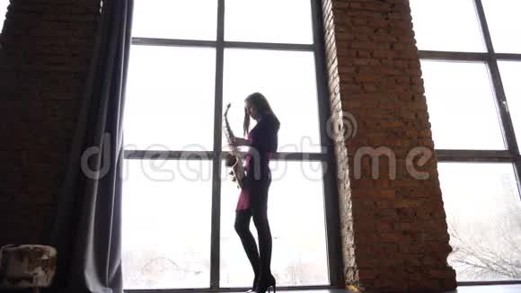 短裙女孩在大窗户附近的复古房间里玩萨克斯管视频的预览图